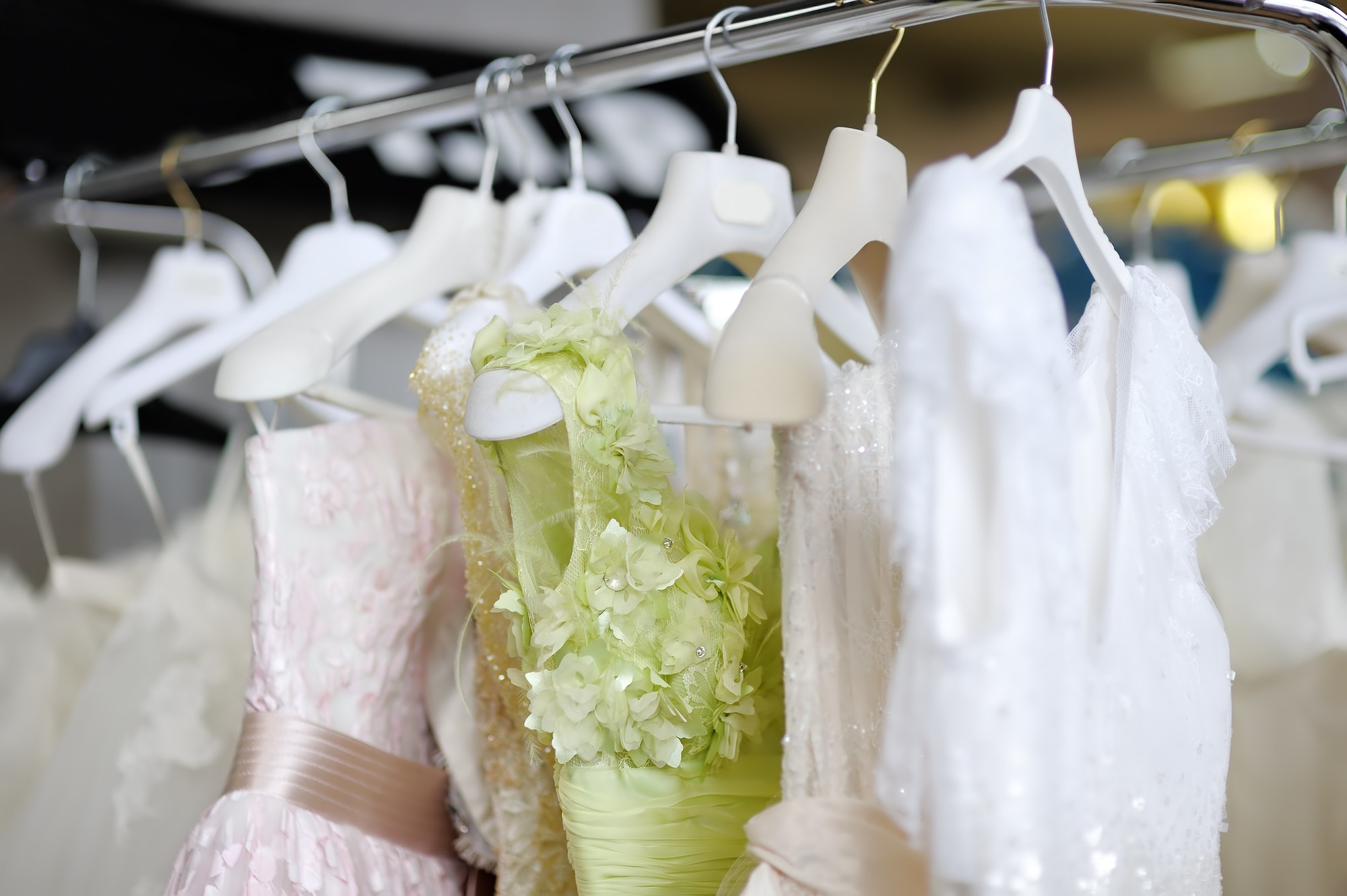 Few beautiful dresses on a hanger in wedding salon or atelier sewing studio.