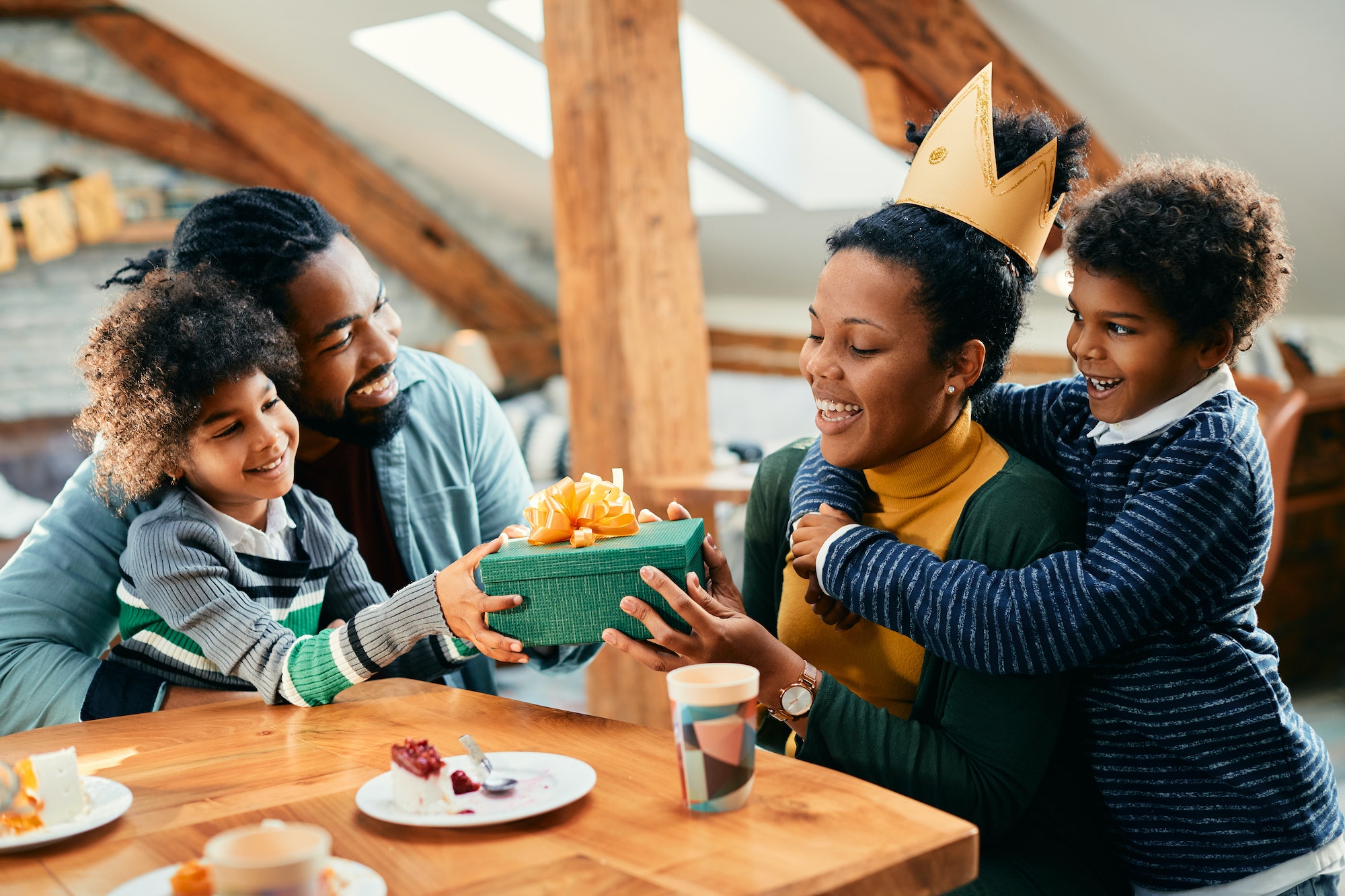 Happy black woman receiving gift from her family during Birthday party at home.
